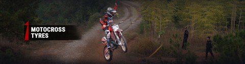 un competidor de motocross en mitad de un salto saludando al público